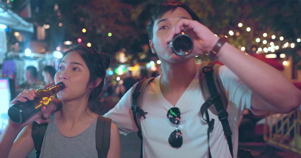 Adolescents d'origines asiatiques buvant une bière dans un festival de musique.