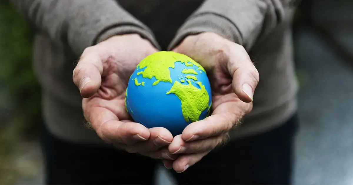 Mains tendues d'un homme tenant une petite planète dont les pays sont recouverts de vert pour signifier l'arrivée du chanvre comme solution médicale.