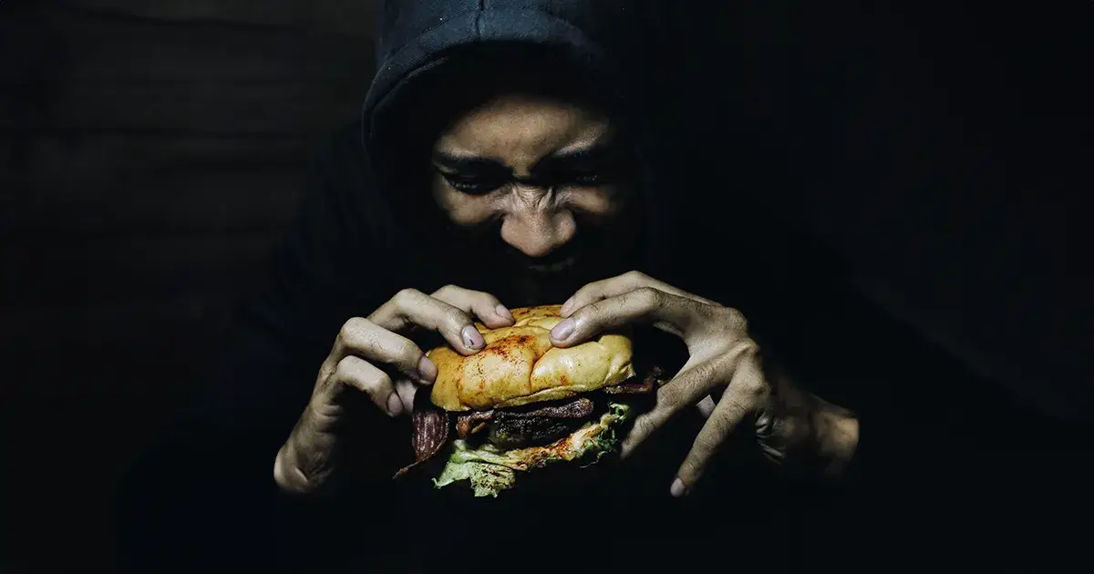 Homme mangeant un hamburger avec un joint de CBD