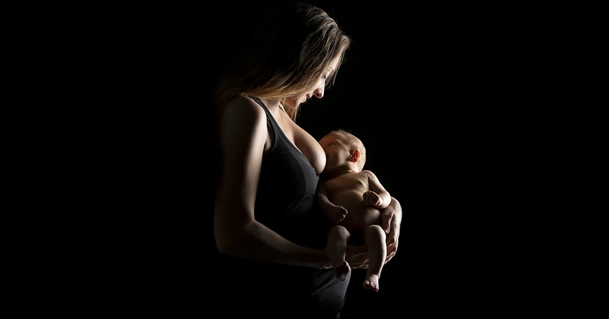 Photographie studio d'une femme entrain d'allaiter au sein son nouveau né.
