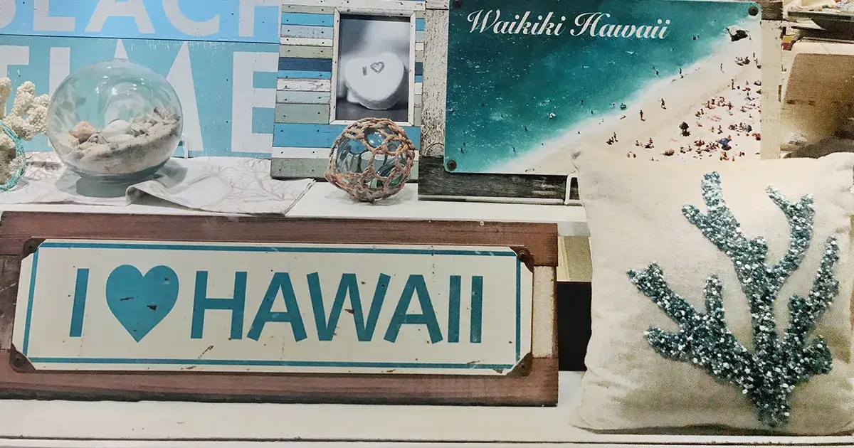 Plaque notée "I love Hawaï" disposés sur des souvenirs de vacances et des cartes postales de l'archipel.